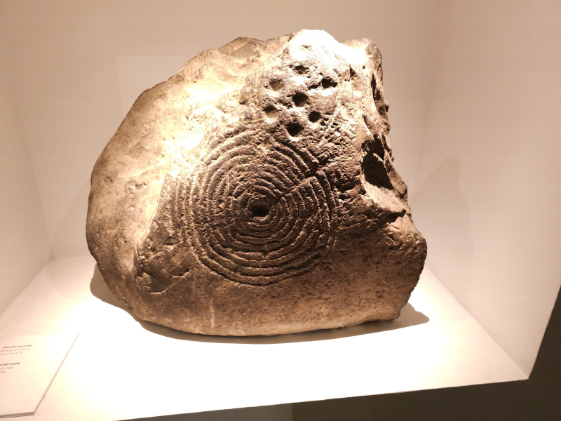 This looks like gold, but that is because of the lighting. It is actually a carved rock from the late bronze age.