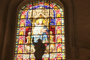 Silhouette of statue against stained glass